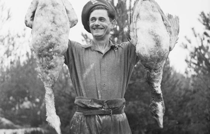 man in army uniform holding up geese