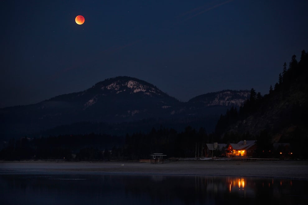 Orange moon over cabin and mountain